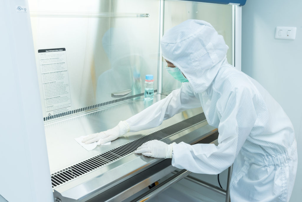 A scientist in sterile coverall gown using alcohol 70% and cleanroom wipes for cleaning Biological safety cabinet(BSC.)