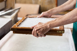 Cropped Image Of Worker Dipping Mold In Pulp And Water