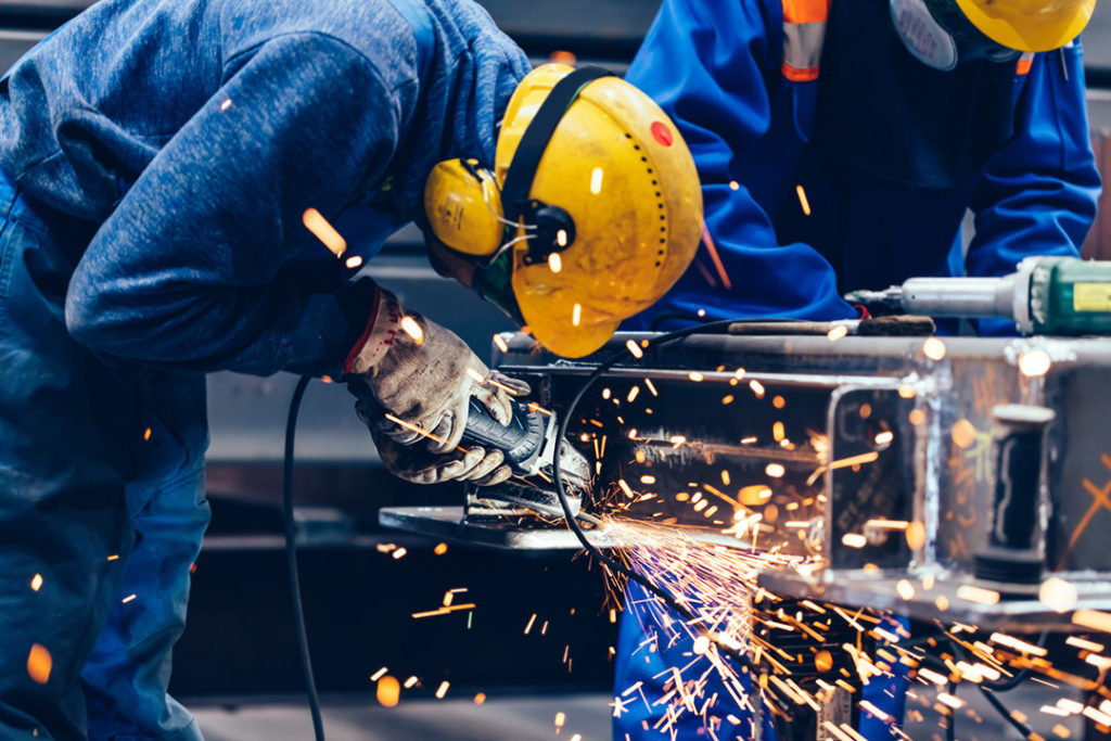 Worker grinding in a workshop. Heavy industry factory