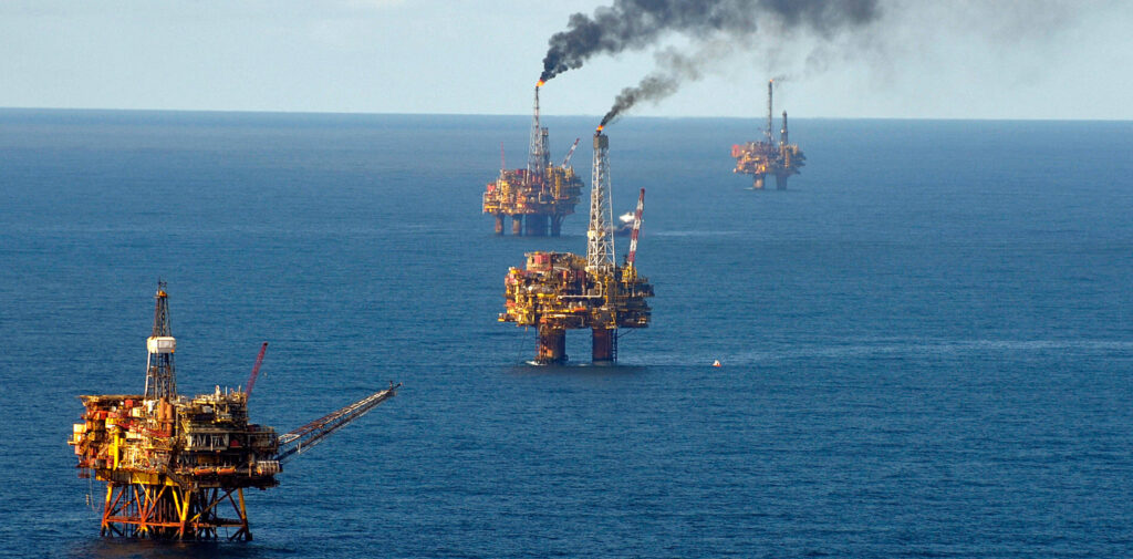 four offshore oil rigs producing thick black smoke in the ocean